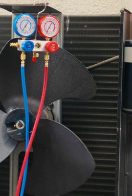 Jib down close up of manifold meters used for checking air conditioner refrigerant in need of maintenance. Set of refrigerant levels benchmarking tool mounted on condenser