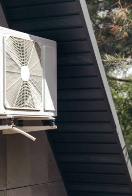External unit of an air conditioner on facade of small wooden forest house
