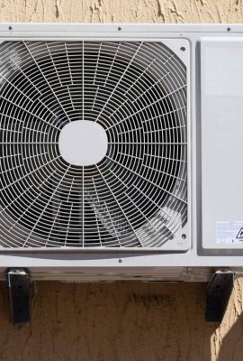 outdoor unit of a domestic air conditioner with a fan outside the building.