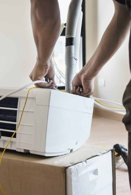 Man is installing air conditioner in housing unit during hot season in Thailand