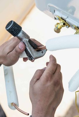 Man is installing wall compressor of air conditioner during hot season